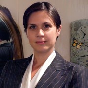 Slightly smiling woman wearing a suit and her dark hair neatly pulled back